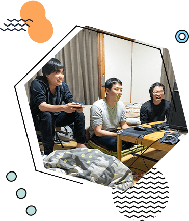 ゲームのコントローラーを持って談笑する3人の社員
