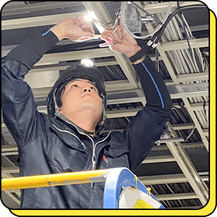 天井の電気配線を点検する社員