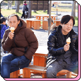 屋外でアイスクリームを食べながら休憩する社員2人