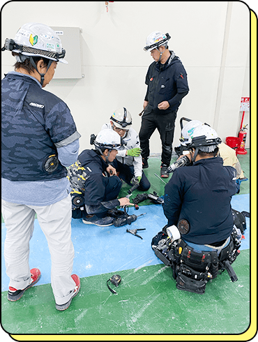 ヘルメットと安全装備を着用し、現場で電気設備の作業を行う社員たち